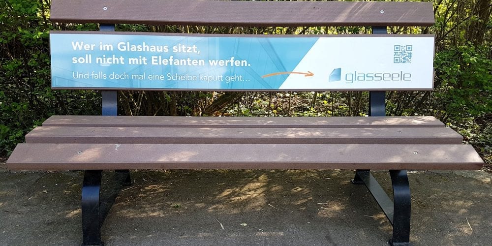 Augsburger Zoo, Parkbank mit Werbebanner von glas seele
